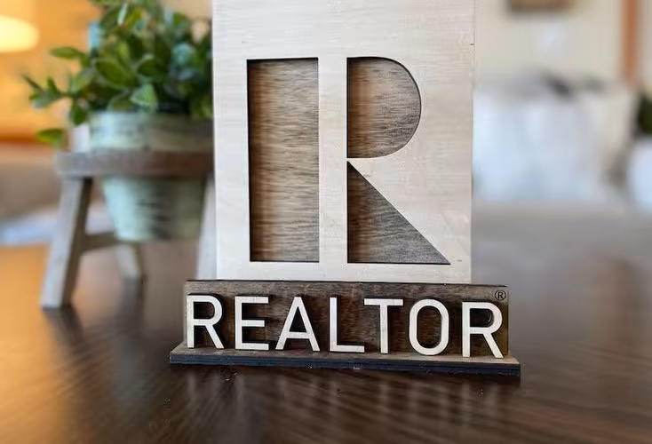 A professional image highlighting the difference between a Realtor® and a real estate agent, featuring the prominent blue "R" symbol of the National Association of Realtors®.
