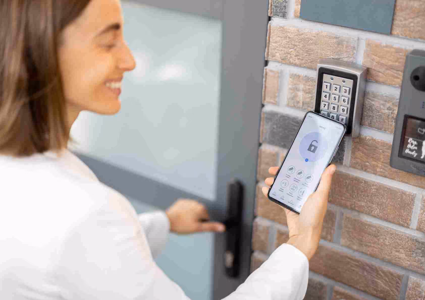 Smart home door locks. Women opening up her front door with her smart phone.