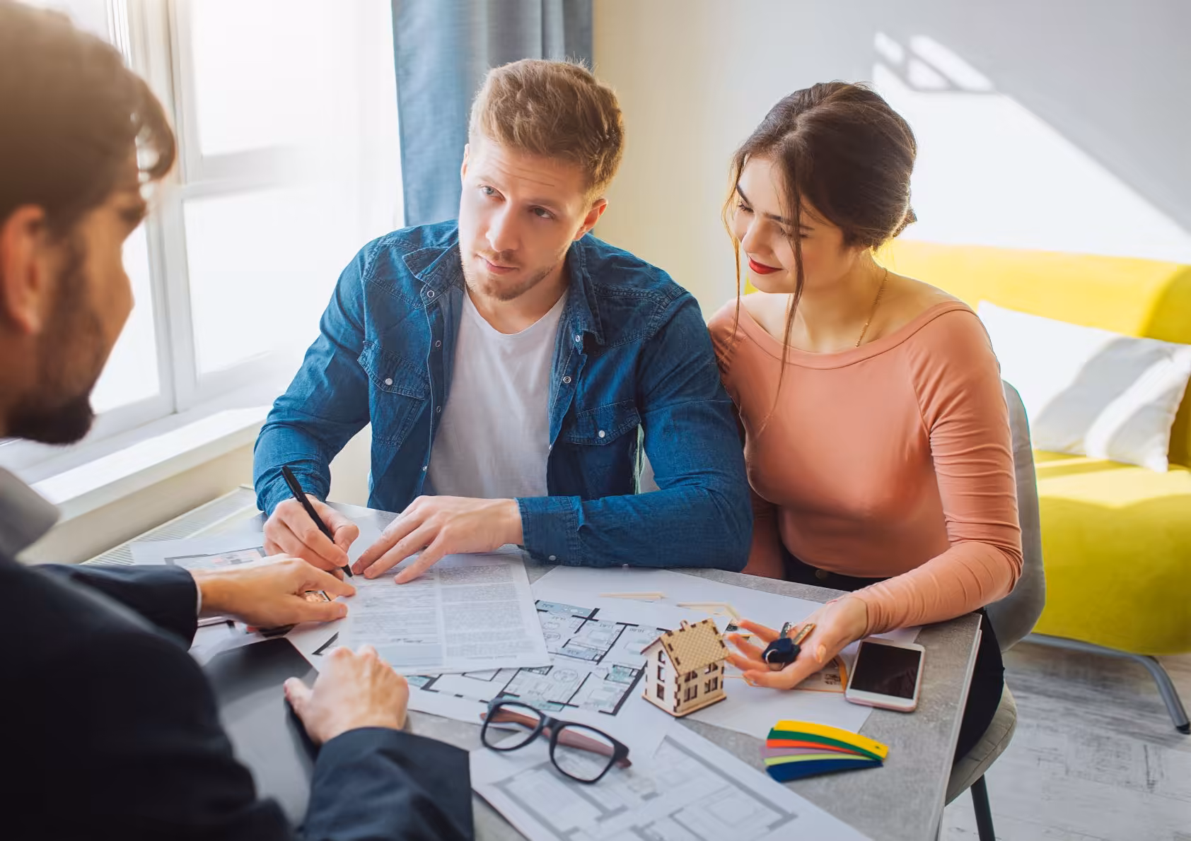 Young couple buying a home. Working with a Real estate professional on closing day. 